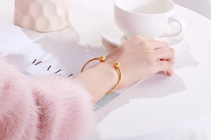 Minimalist gold-plated open spherical cuff bracelet styled on a wrist with cozy aesthetic