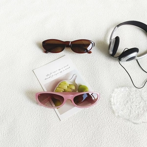 Detail of vintage cat-eye sunglasses in tortoiseshell and pink on a textured background