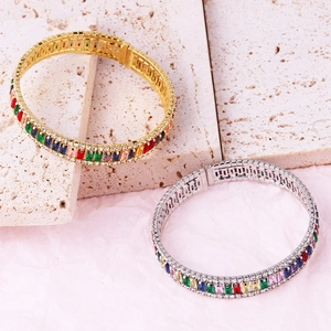 Detail of luxury bangle with colorful baguette zircons in gold and silver finish