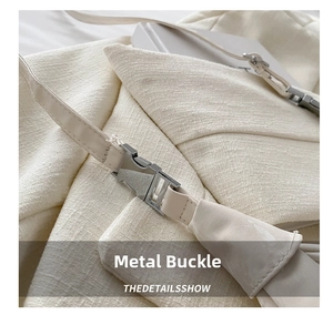 Close-up of beige textured fabric handbag featuring a polished silver metal buckle closure