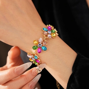 Close-up of vintage gold bracelet with colorful gemstone flowers worn on wrist