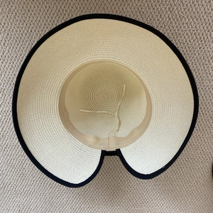 Vista superior de sombrero de paja beige con borde negro y textura de espiral