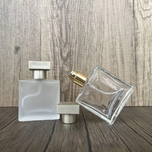 Detail view of square glass perfume bottles in frosted and clear finishes with metal caps
