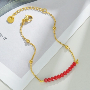 Detailed shot of 14k gold plated chain bracelet featuring red faceted beads and lobster clasp