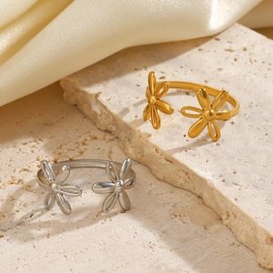 Minimalist stainless steel flower rings in gold and silver finish on velvet surface