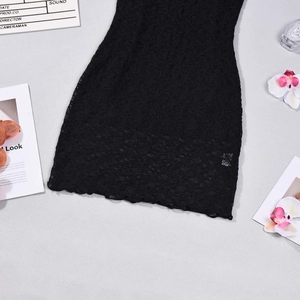 Detail of black lace dress showing scallop hem and intricate floral pattern texture
