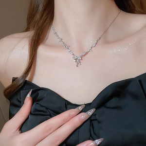 Close-up of sparkling zircon bow and star pendant necklace on female model's neckline