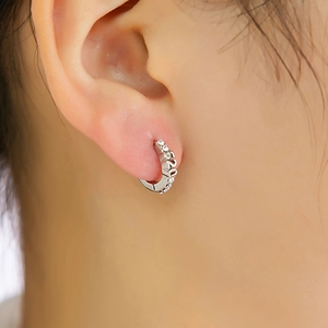 Gros plan d'une boucle d'oreille géométrique en argent avec perle et gravure 520