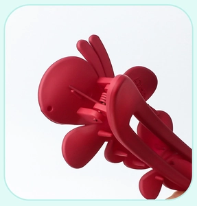 Close-up of a large red matte butterfly hair clip showing its internal spring structure