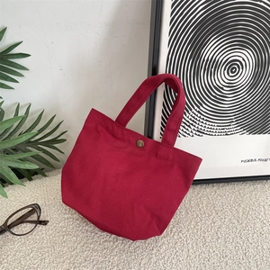 Minimalist burgundy canvas tote lunch bag with metal snap button on white rug