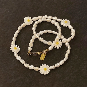 Macro detail of Baroque pearl necklace featuring a daisy charm and S925 silver clasp