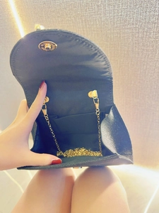 Detail showing internal compartment and golden snake chain of black glitter evening bag