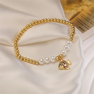 Detail of beaded bracelet with gold beads, white pearls and colorful fish charm on silk