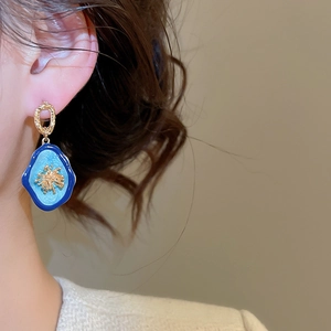 Gros plan de boucles d'oreilles vintage en émail bleu avec anneaux dorés texturés