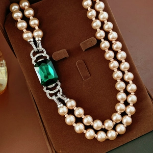 Dettaglio collana di perle vintage a doppio strato con smeraldo e chiusura con diamanti