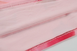 Détail du tissu en maille dégradé rose avec des coutures surjetées de qualité sur la doublure