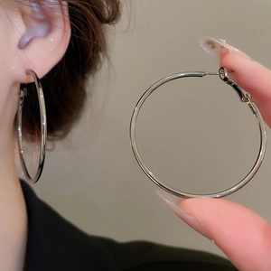Close-up of classic silver metal hoop earrings with a high-polished finish on the ear