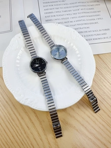 Detail view of silver chain strap minimalist women's quartz watch in blue and black dials