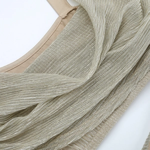 Detail of champagne gold metallic pleated fabric with elegant shoulder strap stitching