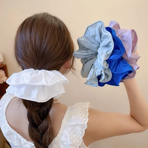 Chouchous géants en tissu blanc, bleu et lilas présentés sur les cheveux et en main