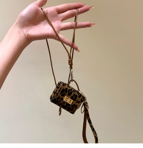Detail of mini leopard print leather bag charm with golden metal twist lock and lanyard