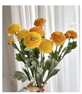 Close-up of yellow and orange artificial ranunculus flowers with flocked green stems