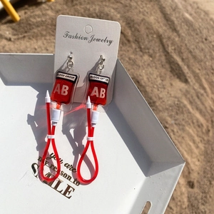 Detailed view of creative blood bag earrings with AB group label and red infusion tube