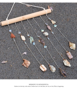 Detail view of colorful natural crystal stone wind chime with wooden rod and metal chains