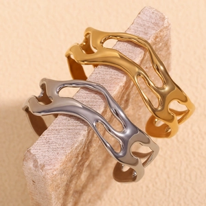 Detailed macro view of 18K gold and silver wavy hollow bangles on natural stone