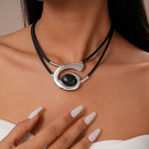 Detail of silver spiral pendant with black oval gemstone on double-layer neck cord