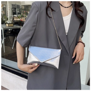 Gros plan du sac enveloppe argenté avec bandoulière chaîne et texture brossée