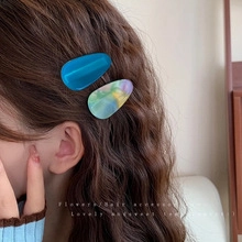 Detail of blue and marble resin hair clips on wavy brown hair for an elegant look