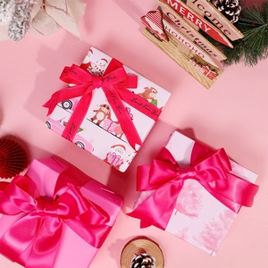 Pink Christmas wrapping paper rolls with elk and tree patterns and festive silk ribbons