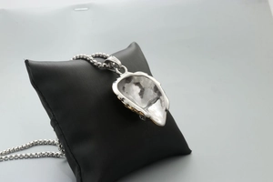 Close-up of silver lion face shield pendant necklace on black leather cushion display