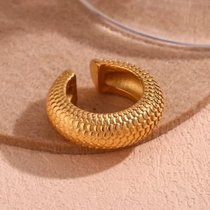 Macro view of C-shaped golden earrings with intricate fish scale embossed texture