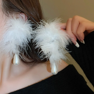 Detail view of long white ostrich feather earrings with a large teardrop pearl drop