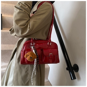 Detailed view of a red patent leather shoulder bag with pockets and a plush bear charm