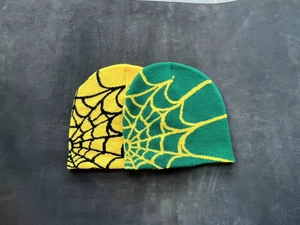 Detailed view of yellow and green knitted beanies with jacquard spider web patterns