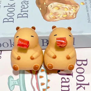 Pair of Capybara squeeze toys with red whistles on a book background, cute animal shape