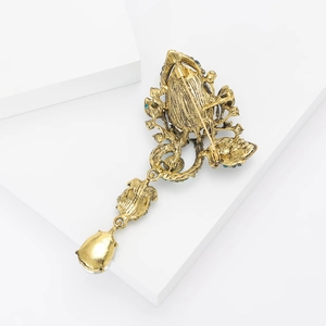 Close-up of golden vintage brooch back showing safety pin structure and pendant detail