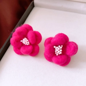Macro shot of pink wool felt flower earrings with delicate white bead centers