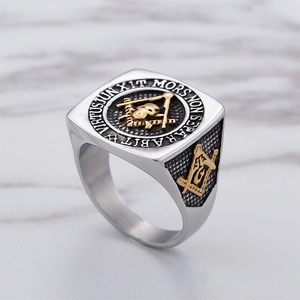 Vintage stainless steel Freemason skull ring with gold accents on marble background
