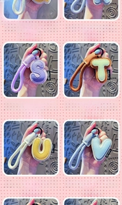 Detail of leather alphabet keychains S, T, U, V with braided ropes and metal hooks