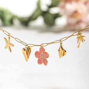 Detail of 18K gold stainless steel bracelet with pink enamel flower and sea pendants