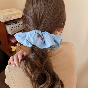 Close-up of light blue fabric scrunchie with cherry embroidery and white pearls