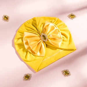 Detail of baby turban hat with oversized yellow satin bow and sparkling rhinestone