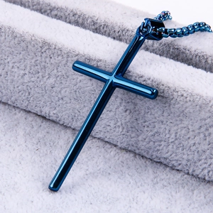Macro shot of blue stainless steel cross pendant on grey velvet display base