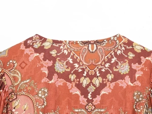 Dettaglio dello scollo rotondo bohémien con stampa paisley nei caldi toni della terracotta