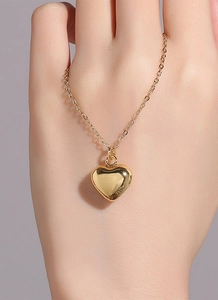 Detail showing high-polish gold heart pendant and fine link chain on female hand