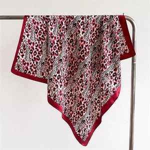 Detail of leopard print satin scarf with elegant red border draped on a metal rack